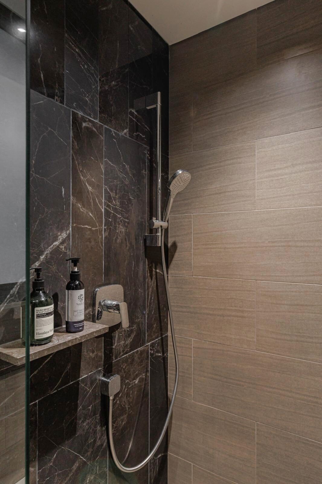 Dark marble shower enclosure meeting warm timber-look tile, bathroom interior by Porterbox Studio