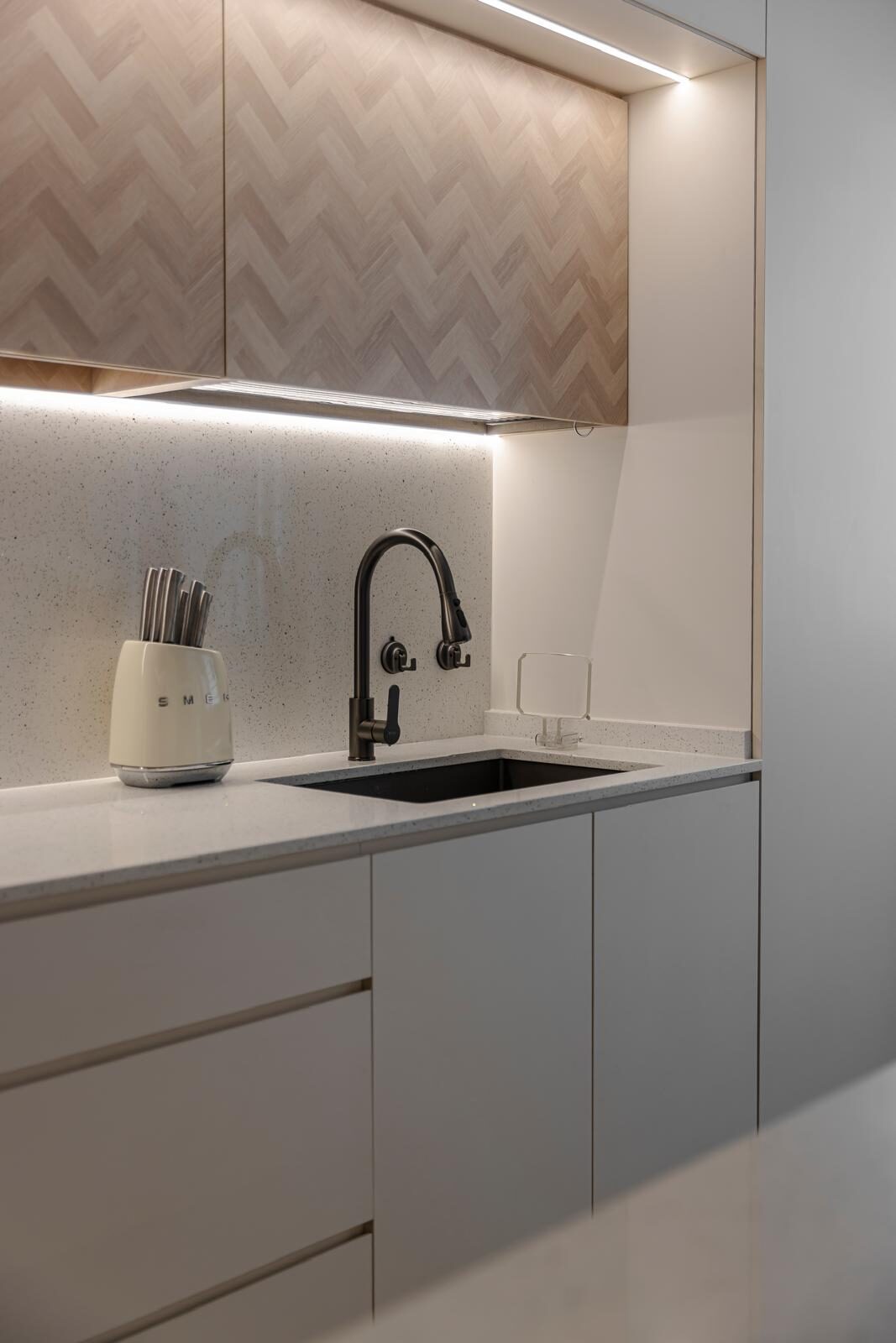 Herringbone oak overhead cabinetry above a speckled stone counter, kitchen interior by Porterbox Studio